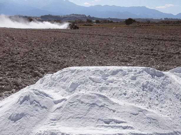 cena fundamental no ciclo agrícola: a preparação do solo. Em primeiro plano, um grande monte de calcário