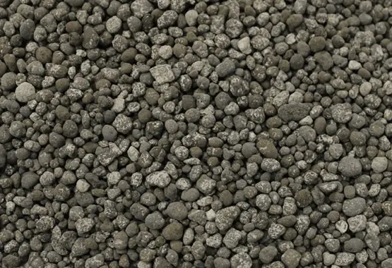 uma visão em close-up de um amontoado de fertilizante granulado. Os grânulos são pequenos, com formatos irregu