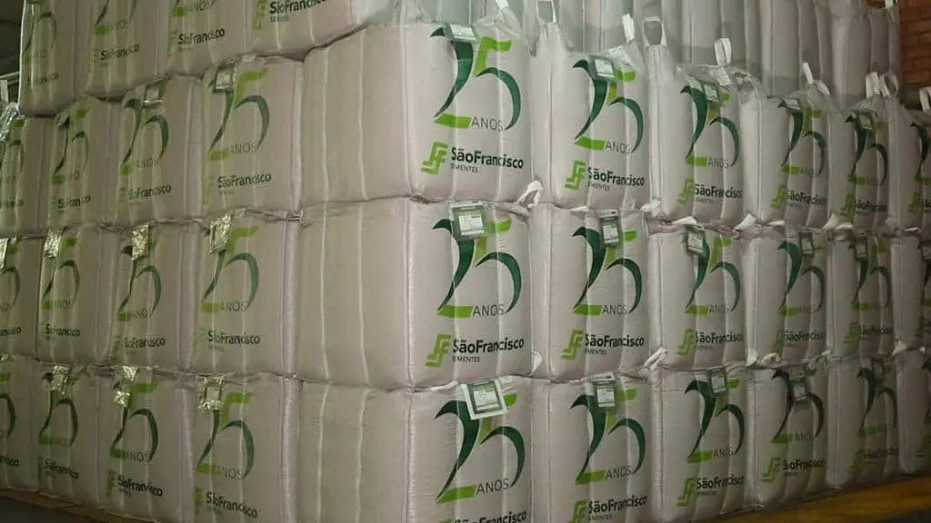 grande depósito com dezenas de big bags (sacos de grande volume) brancos, empilhados de forma organizada em