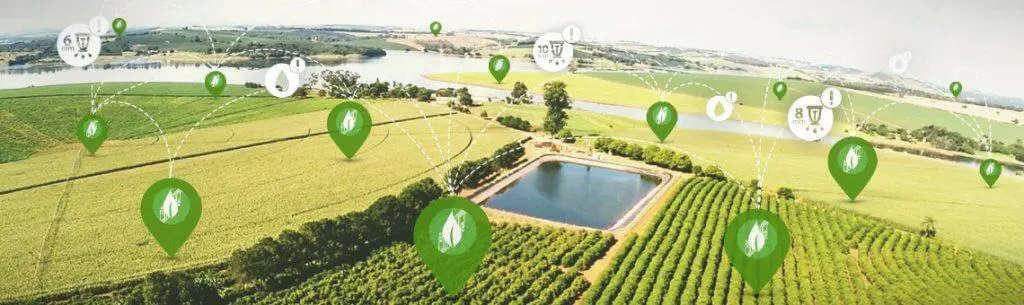 uma vista aérea panorâmica de uma vasta área rural, mostrando diversas plantações, um reservatório de água e u