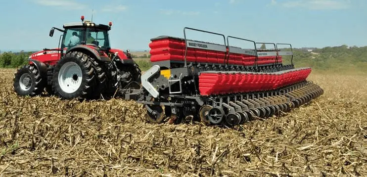 uma operação agrícola em pleno andamento, destacando um trator vermelho da marca Massey Ferguson, modelo de gr