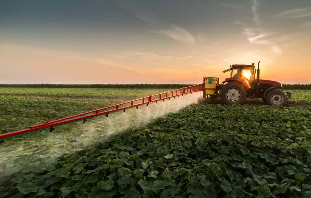 cena de agricultura moderna ao entardecer ou amanhecer. Um trator vermelho de grande porte está posicion