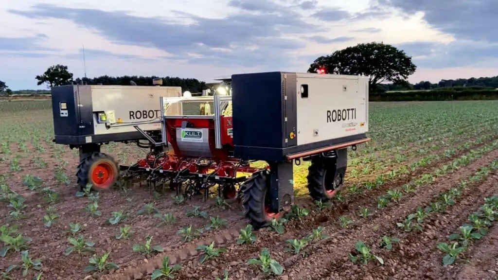 robô agrícola autônomo, modelo ‘ROBOTTI’, operando em uma lavoura durante o entardecer ou amanhecer. O equi