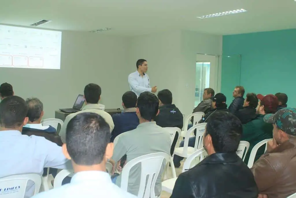imagem retrata um ambiente de treinamento ou uma palestra corporativa, provavelmente focada no setor do agronegócio. Um ins