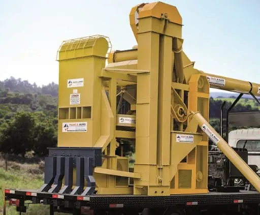 uma unidade móvel de beneficiamento de grãos, um equipamento agrícola de grande porte, pintado em amarelo vibr