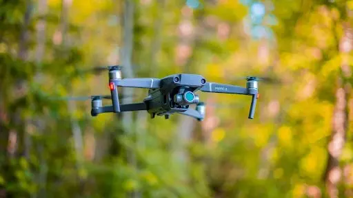 drone moderno, modelo DJI Mavic 2, em pleno voo. O equipamento está em foco nítido, pairando no ar com suas